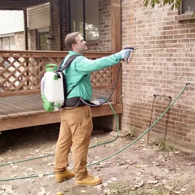 Tech spraying exterior of home