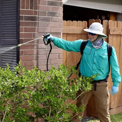 Tech spraying exterior of home