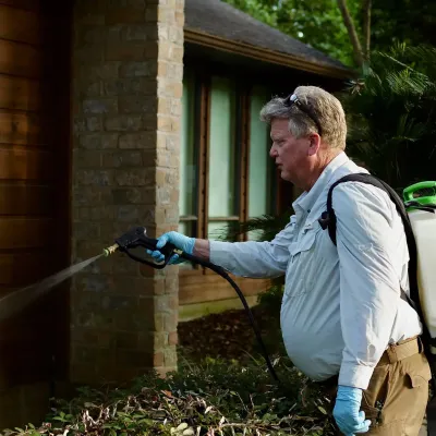 Tech spraying exterior of home